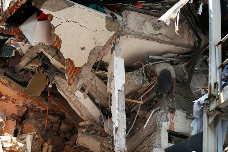 The body of woman hangs crushed by a collapsed building in the neighborhood of Roma Norte, in Mexico City. (Image: AP)